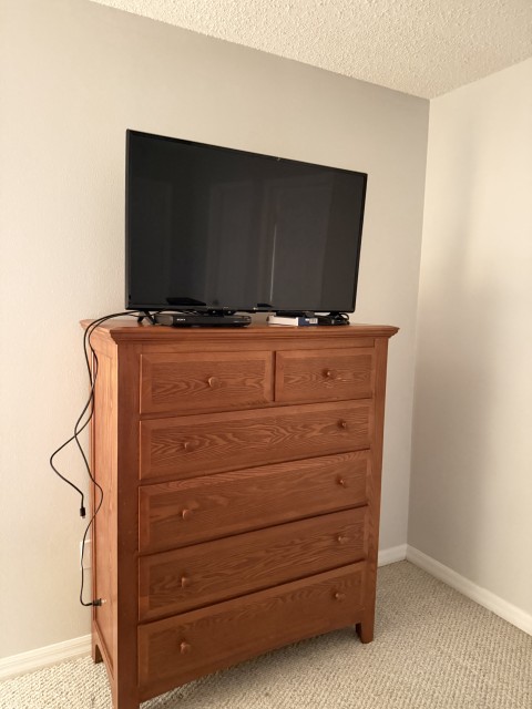 Flat screen TV on tall five-drawer solid oak wood bedroom chest dresser