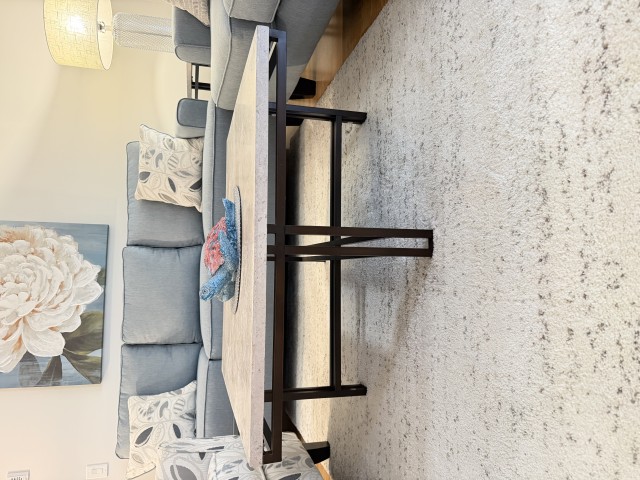 Stone top coffee table with dark metal base in front of blue sectional sofa