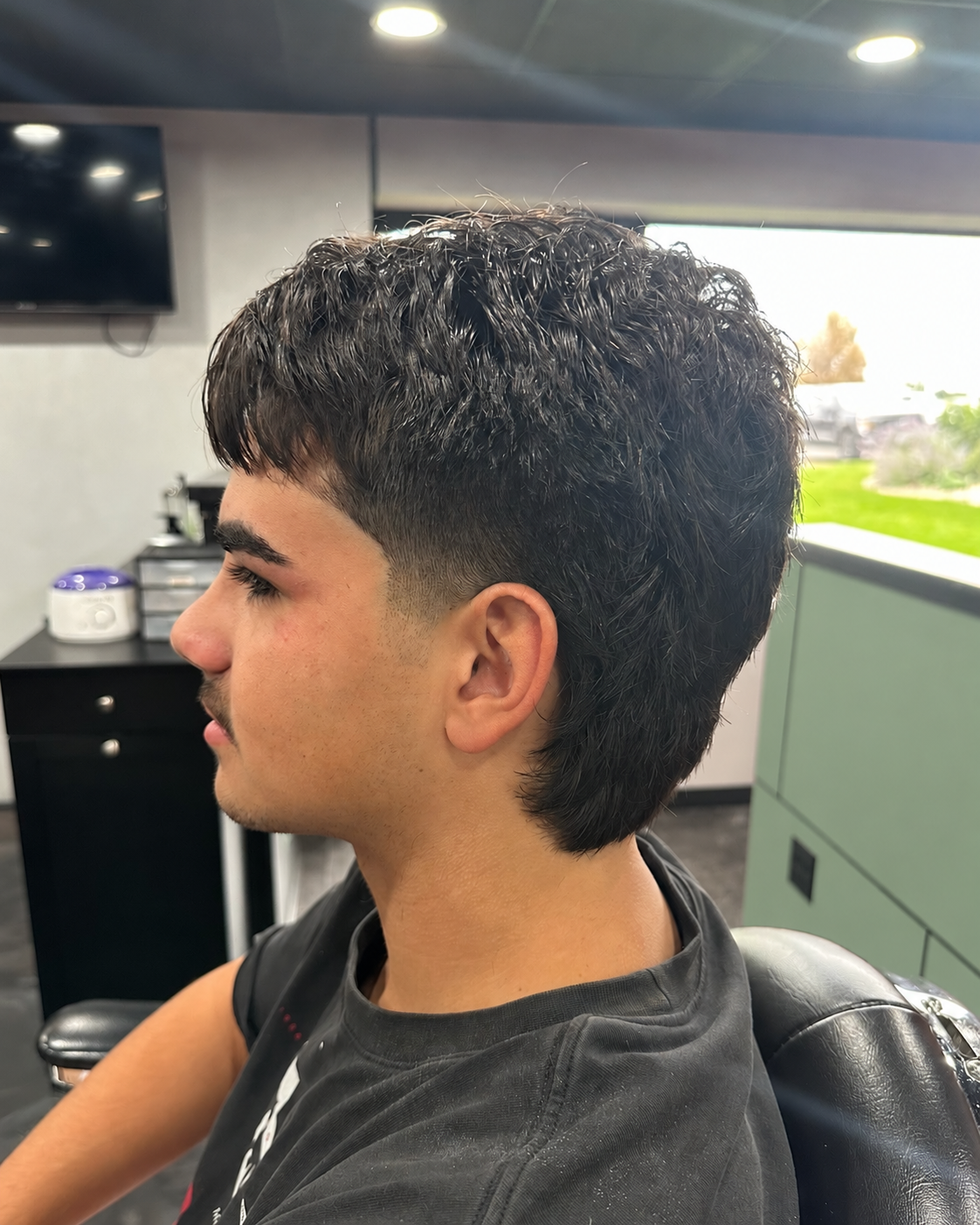 A gentleman with a textured modern taper haircut and clean hairline styled at MANE DISTRICT