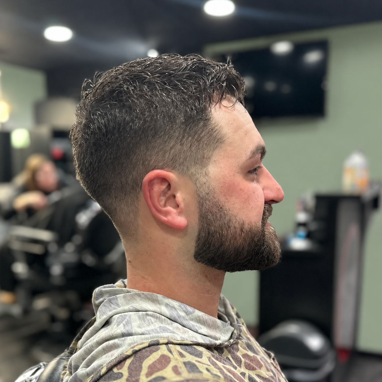 Client with a clean taper fade haircut and groomed beard at MANE DISTRICT