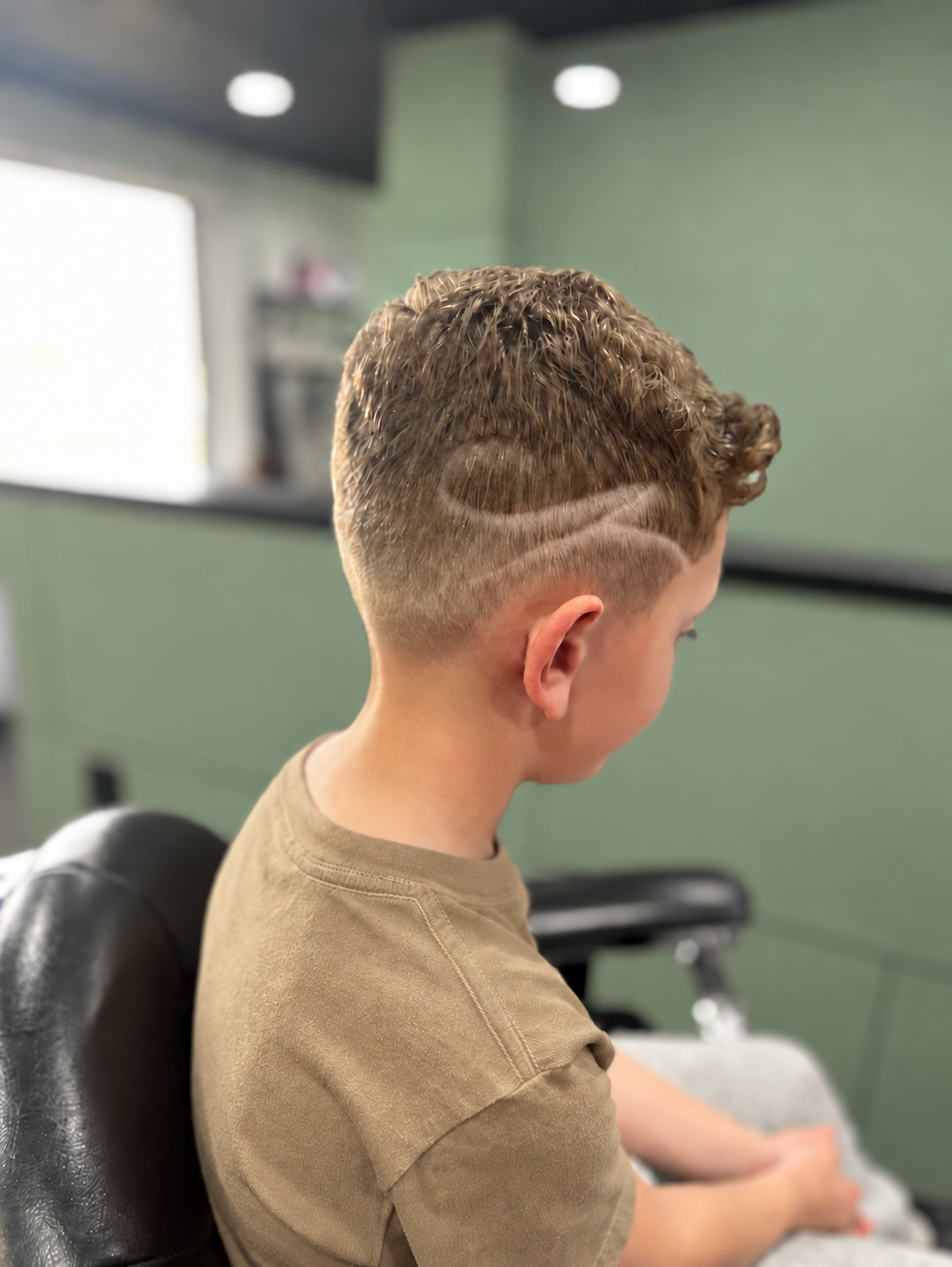 A clean taper fade haircut with custom artistic shaved design lines styled at MANE DISTRICT