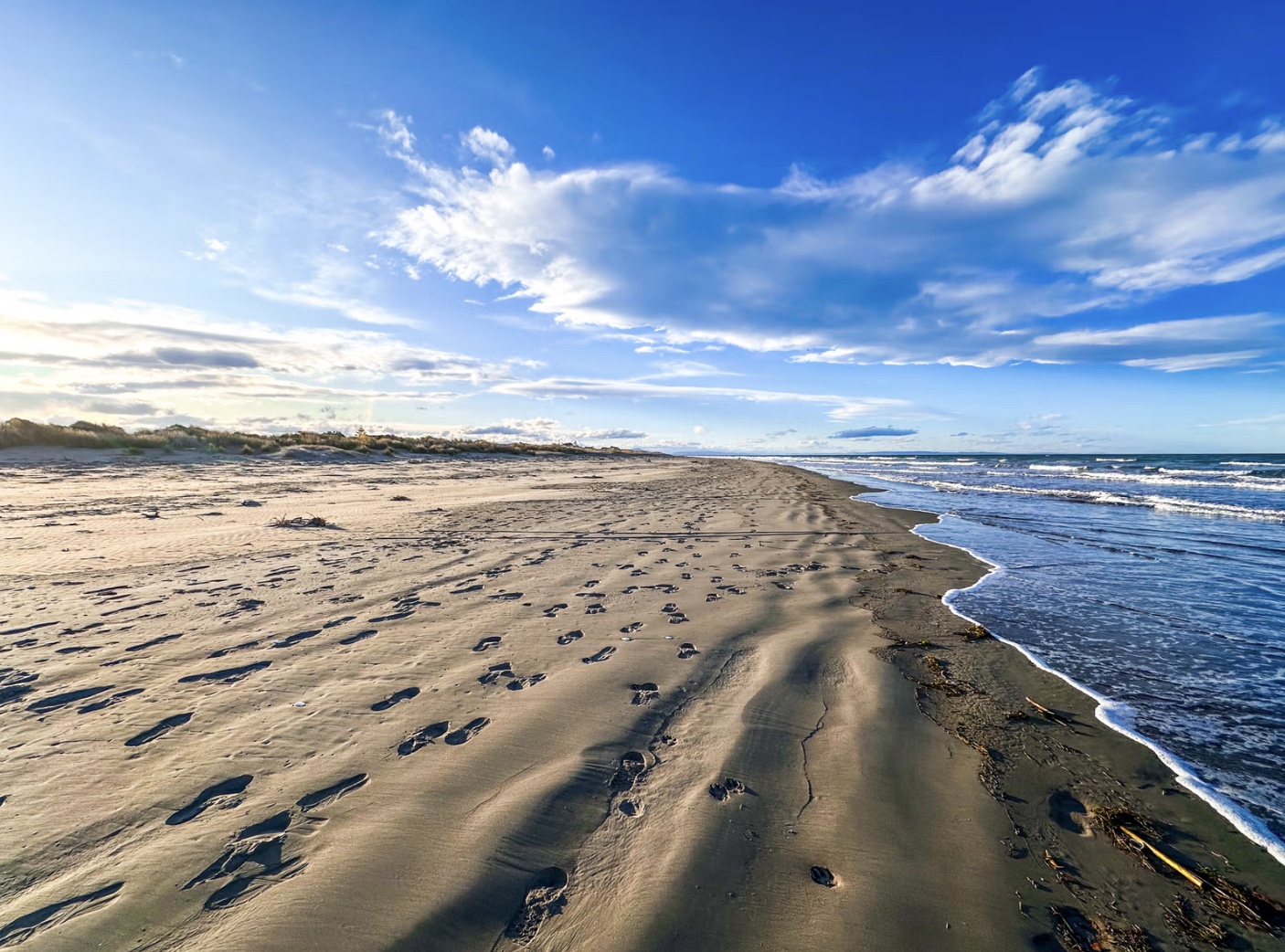 Sandy ocean beach with footprints and surf at Southshore