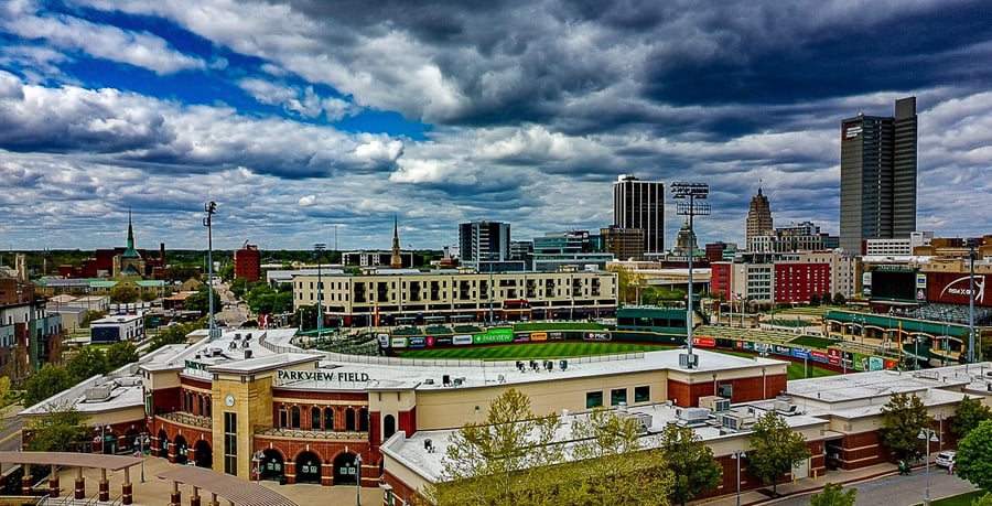 Parkview Field baseball stadium in downtown Fort Wayne under a dramatic cloudy sky.