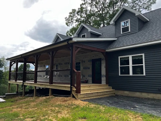 Wrap-around timber frame porch with arched braces and railings on custom home in East Tennessee