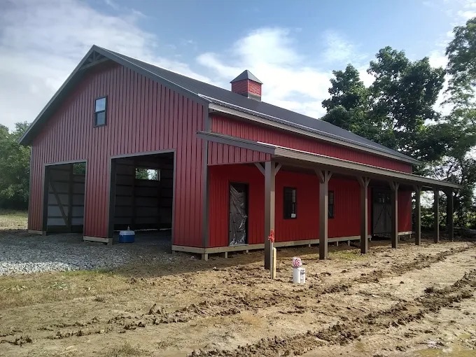 Red metal residential barndominium with stained timber post covered porch in Rutledge, TN
