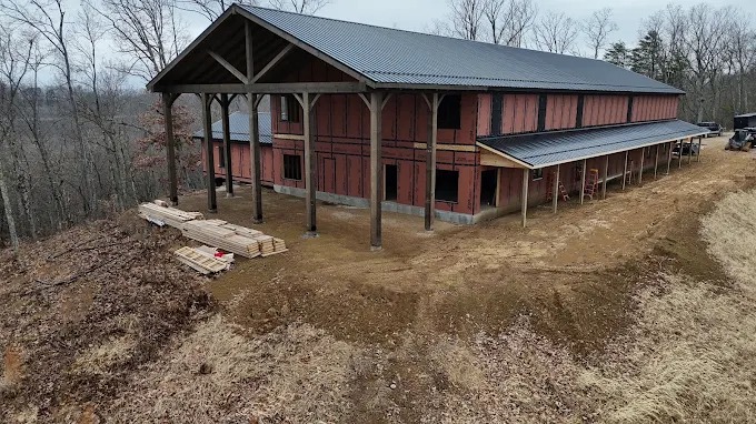 Custom hillside barndominium frame with large timber gable porch in Maynardville, Union County, TN