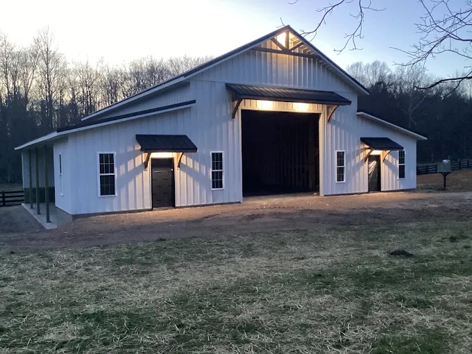 Timber door awnings and timber gable web accent on white barndominium in Rutledge, TN