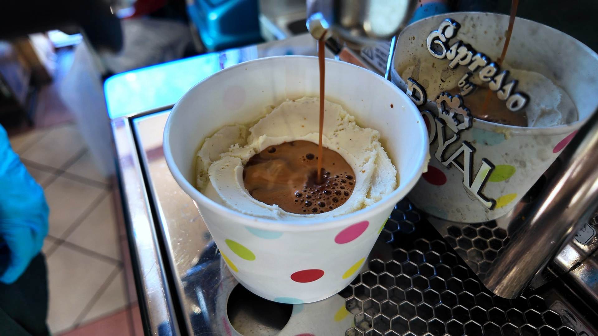 Fresh espresso pouring over a cup of gelato for an affogato al caffè