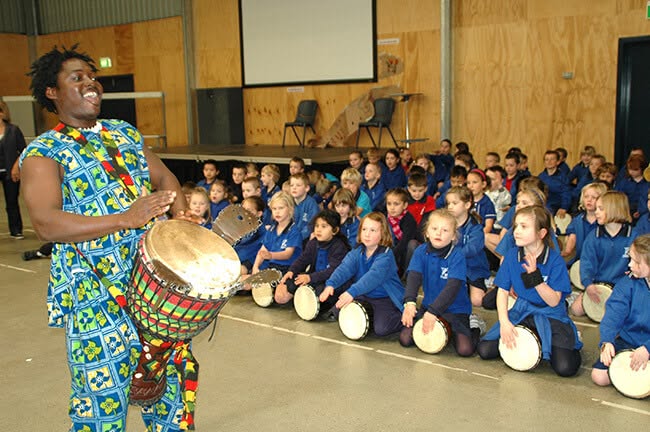 Young children playing djembe drums together during a kindergarten African drumming incursion