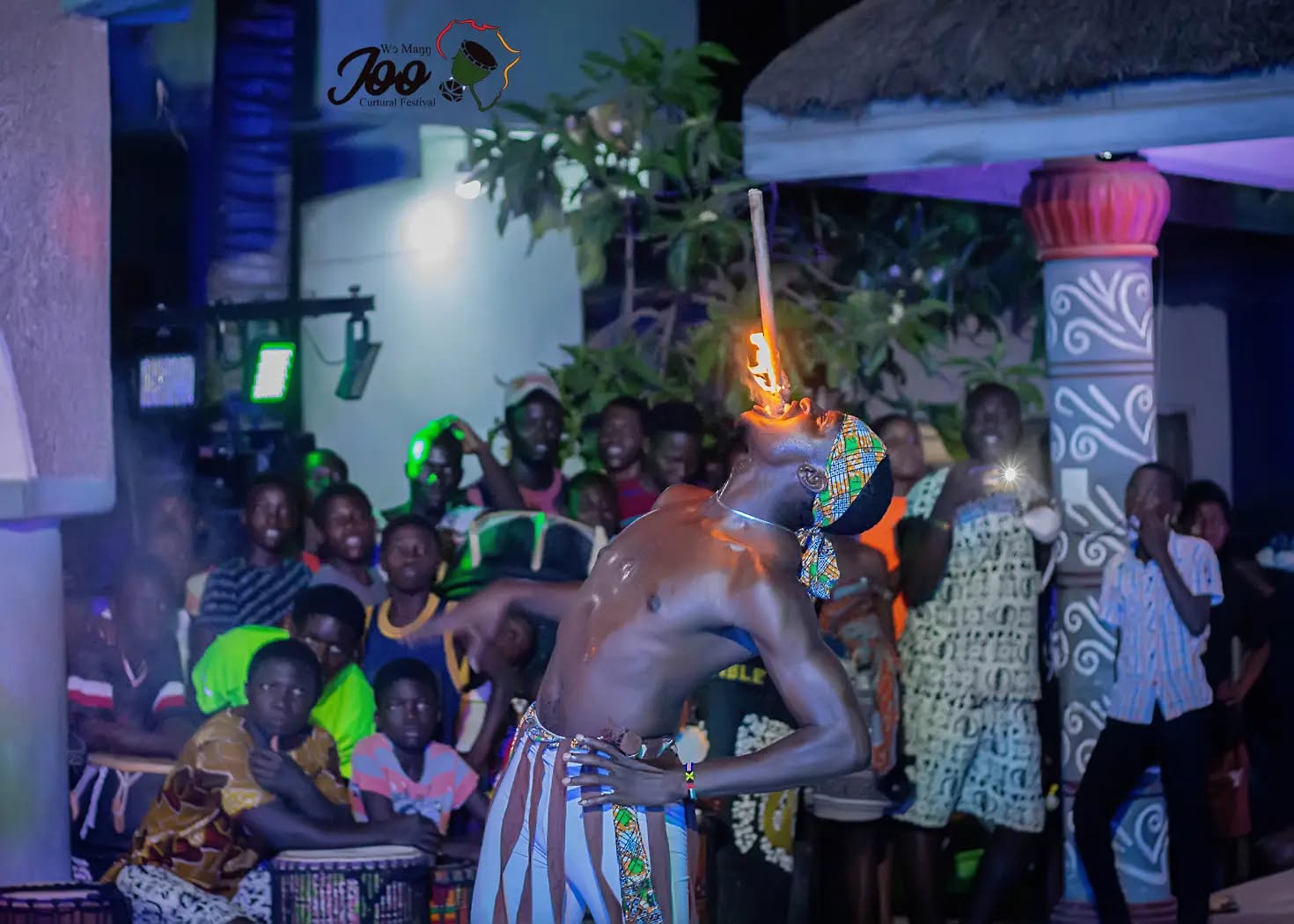 Performers in traditional dress on a night stage under blue and violet stage lighting during an African Beat evening performance