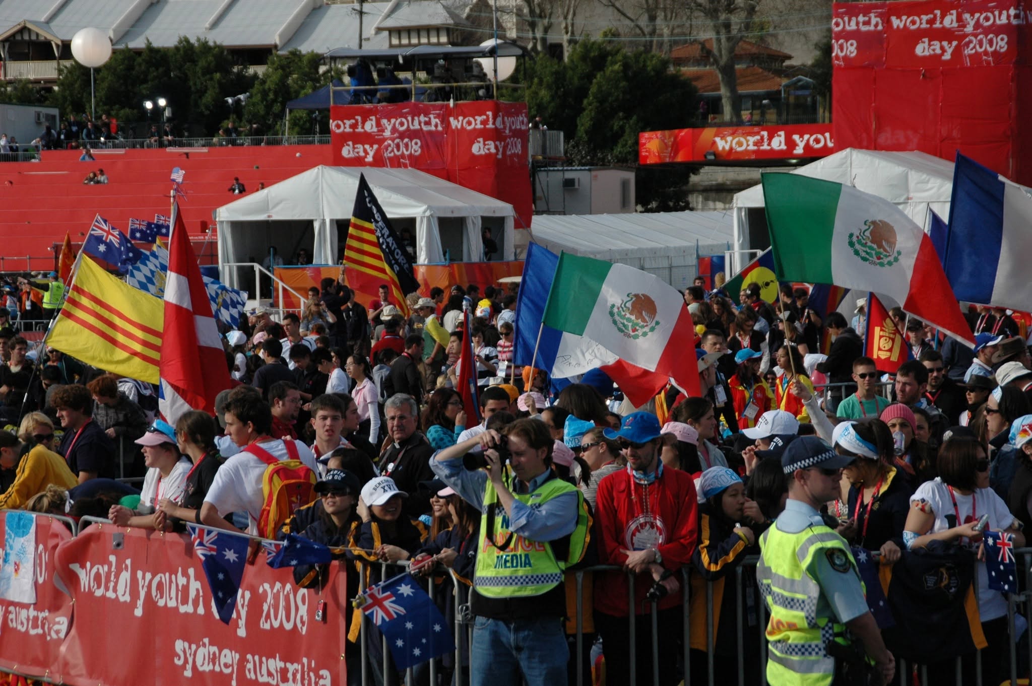 Daytime festival crowd with international flags gathered around an African drumming performance