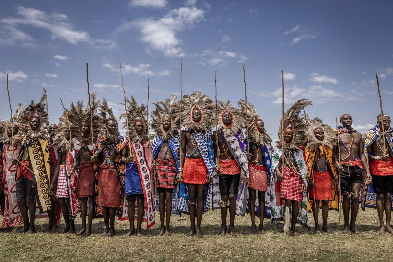 Dancers in traditional headdresses and ceremonial dress performing on an open field at an outdoor cultural event