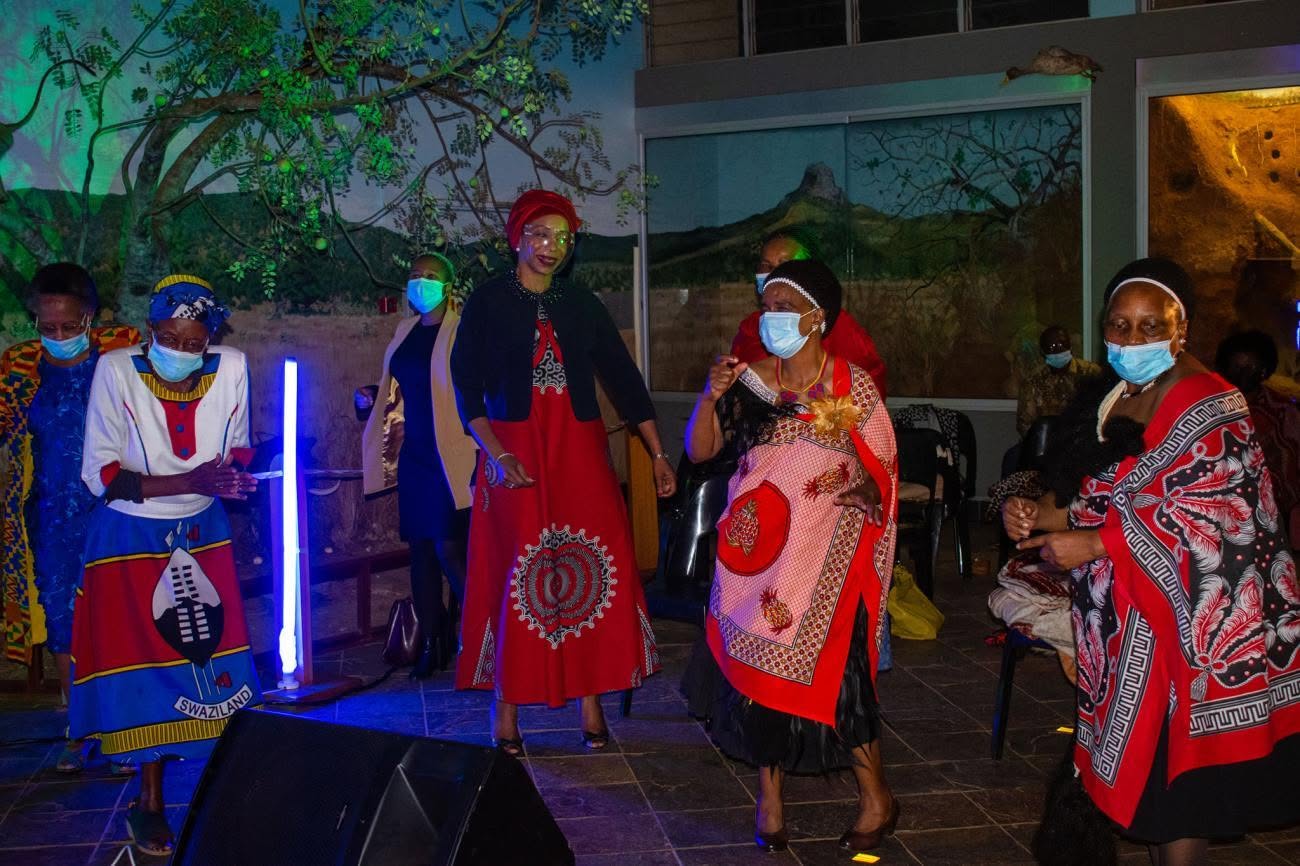 African Beat performers in traditional dress on a night stage under blue stage lighting
