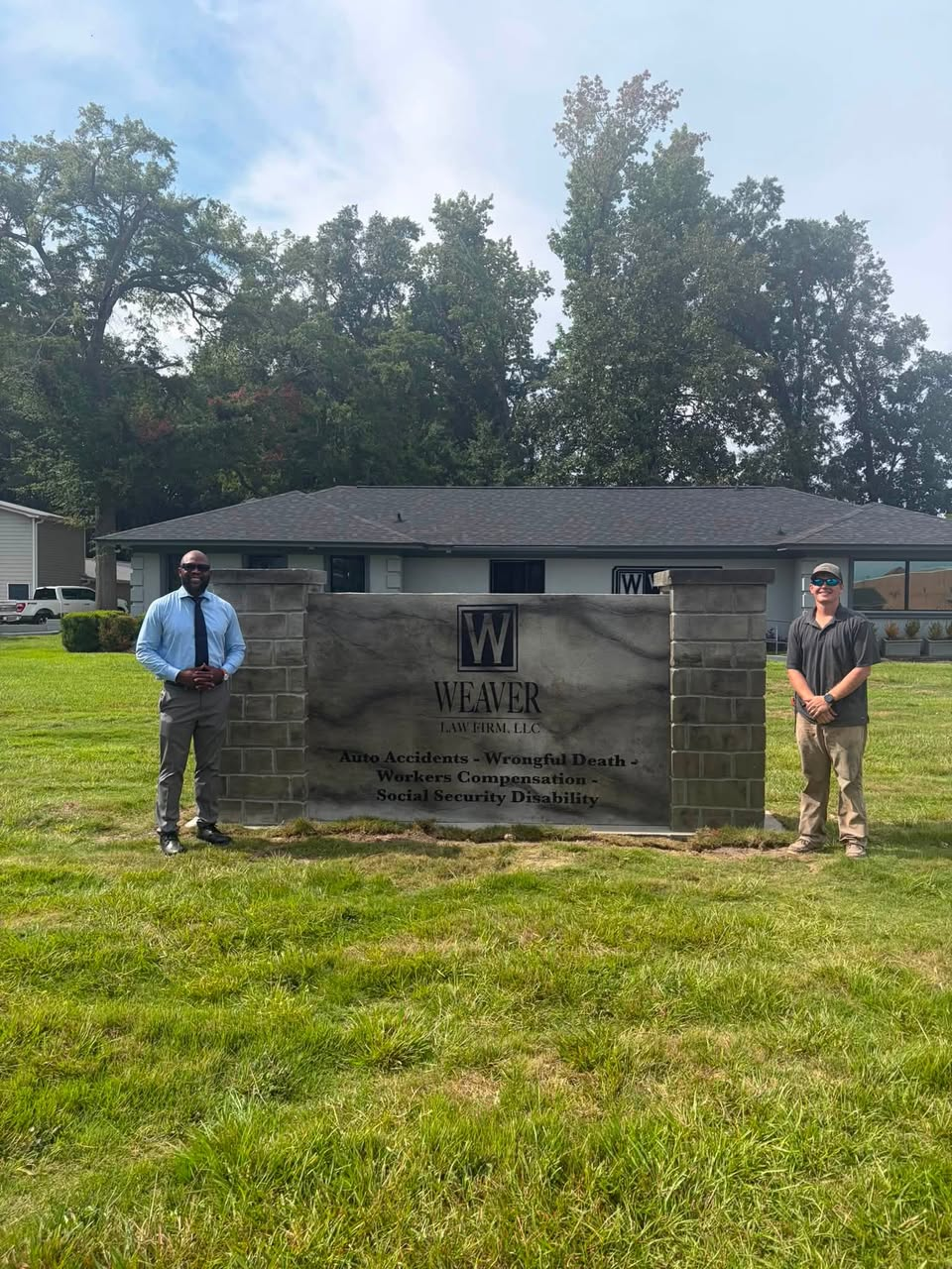 Holt McFadden standing with client by custom stone pillars and engraved law firm monument