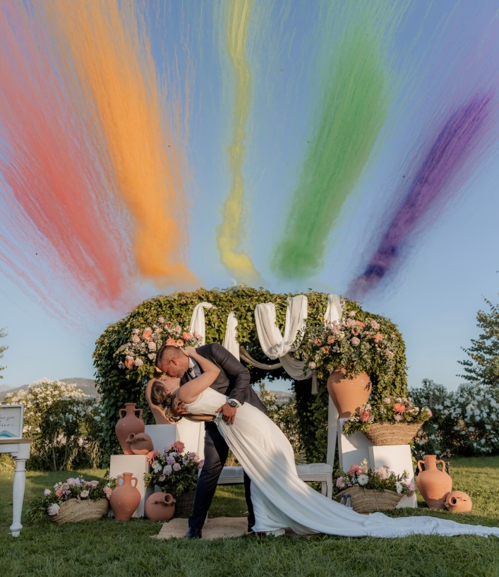 Beso de los novios bajo una lluvia de humo de colores arcoíris