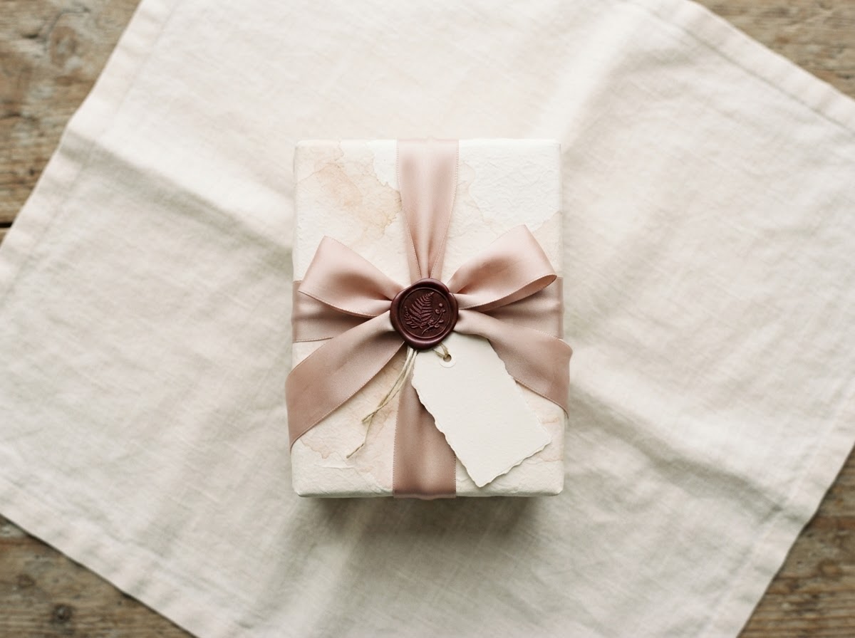 A wrapped gift with a burgundy wax seal and blank gift tag