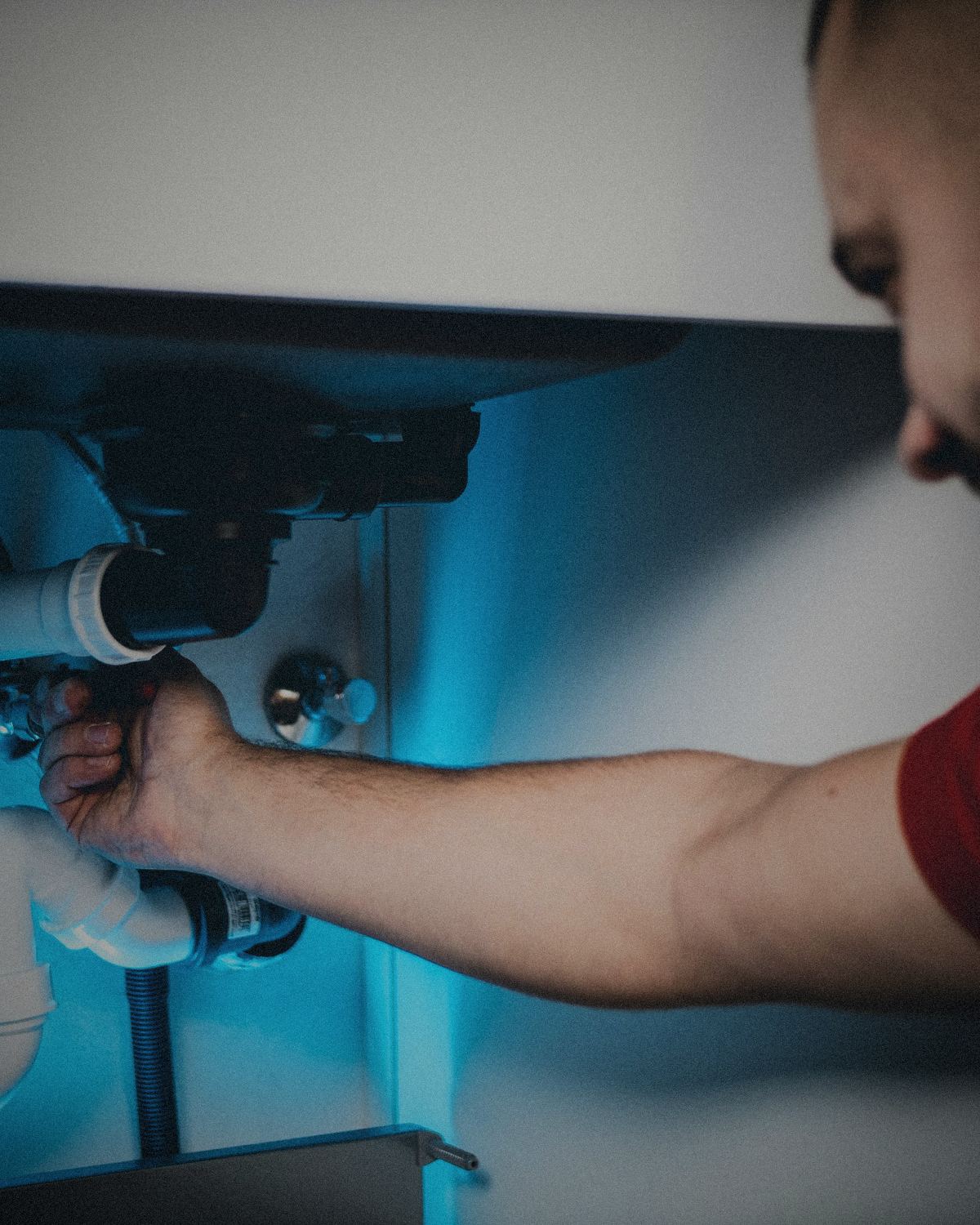 Plumber repairing pipes under a kitchen sink