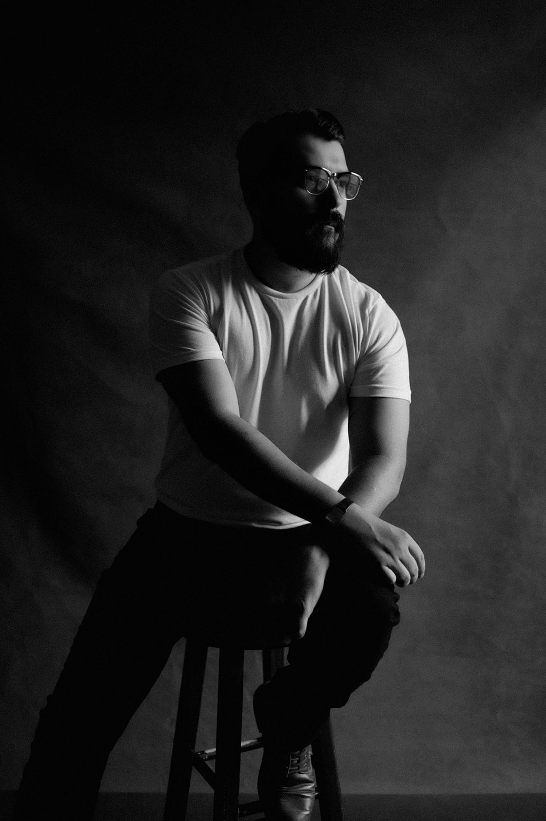 Black and white seated portrait of a man with glasses and beard by Elisa Mitchell Studios