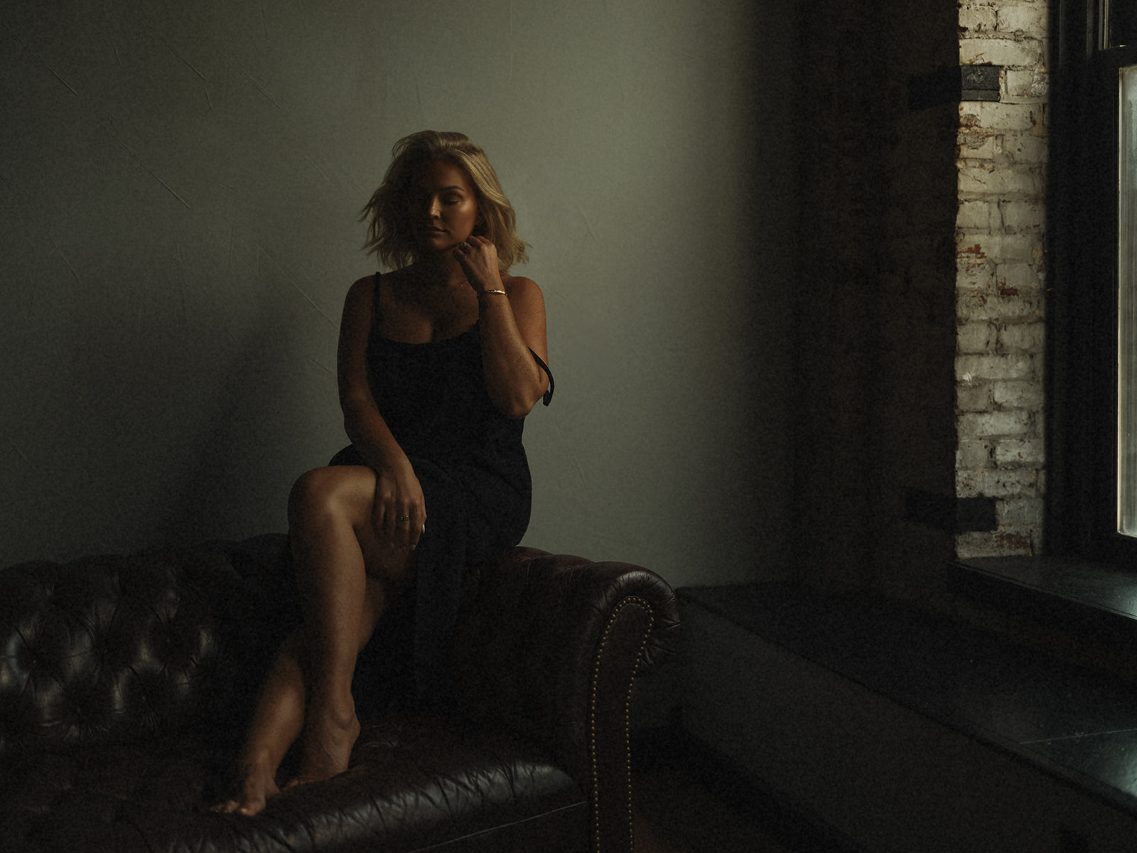 Moody fine art window portrait on leather chesterfield couch