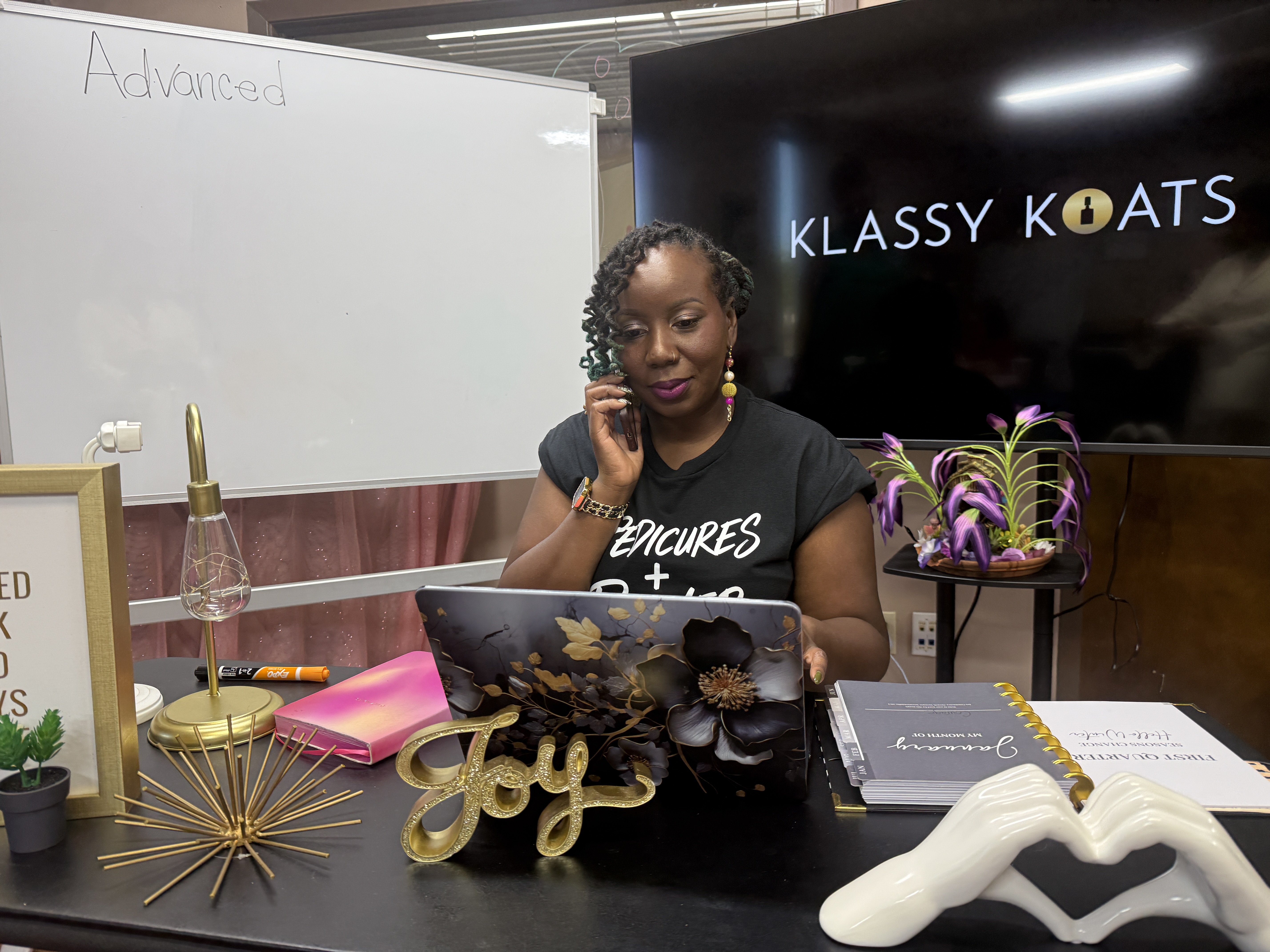 Bre at her desk at Klassy Koats with Klassy Koats screen behind her