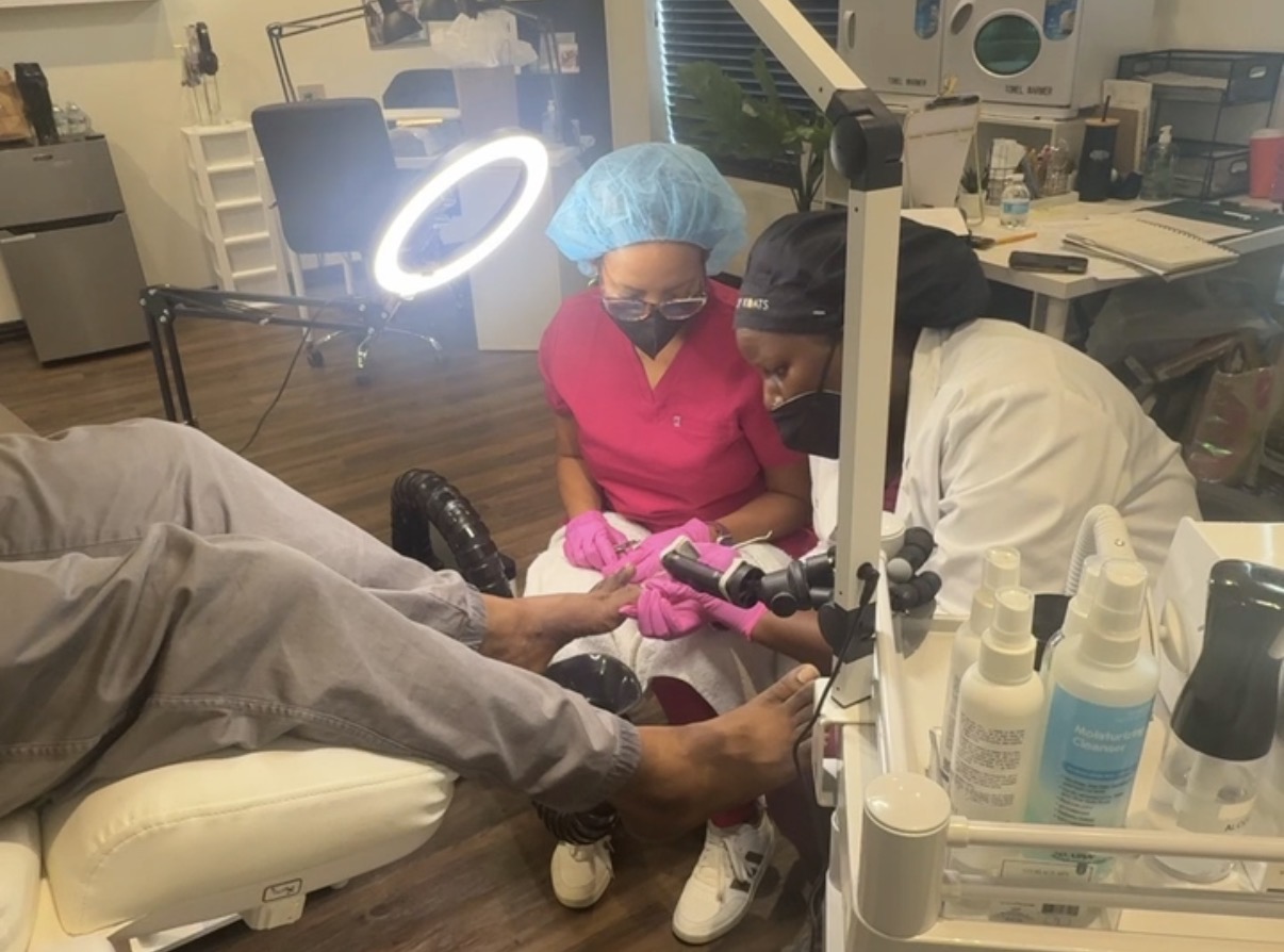 Bre guiding a student through hands-on advanced pedicure in salon chair