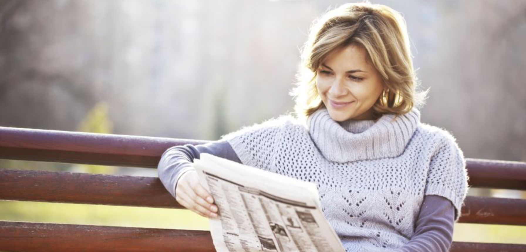 Woman reading Flint Hills Shopper newspaper on park bench