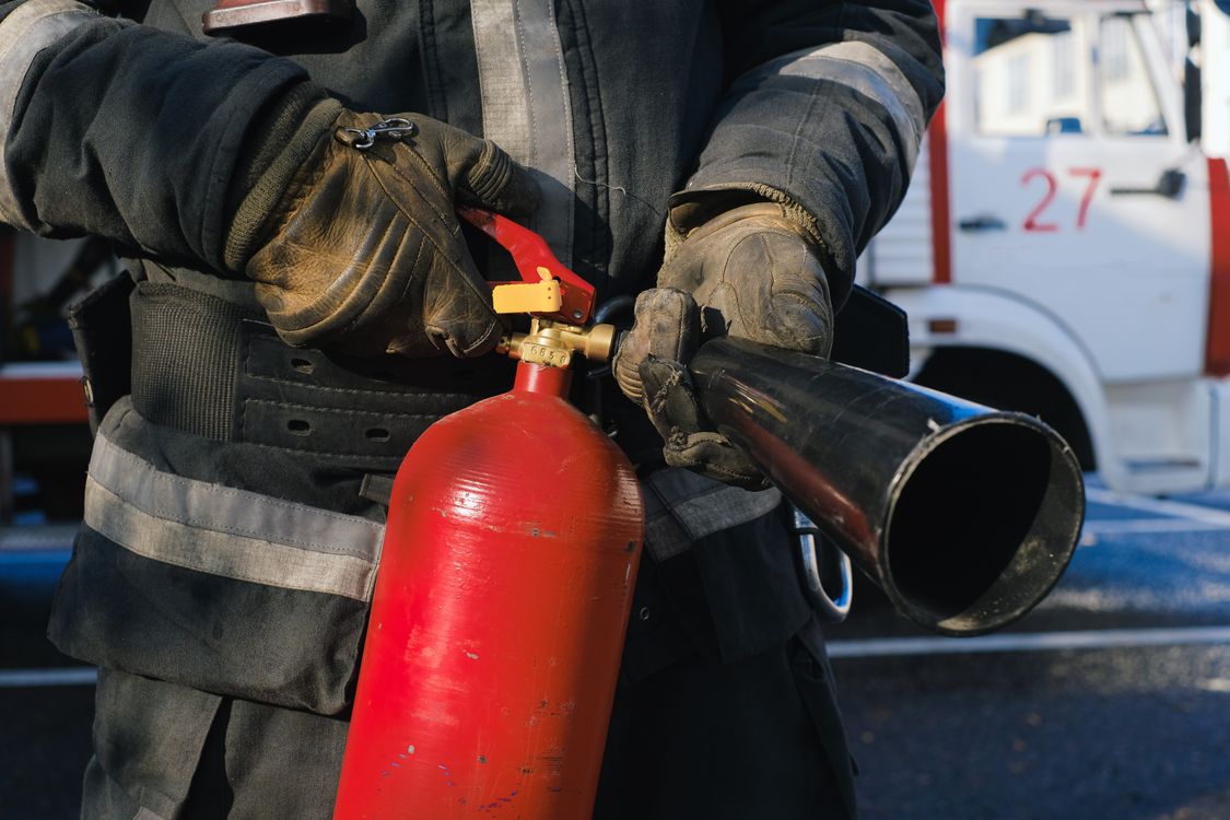 A firefighter holding a red fire extinguisher (illustrative stock photo).