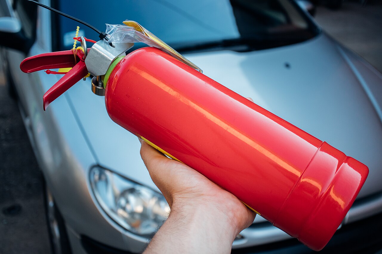 A person holding a red fire extinguisher (illustrative stock photo).