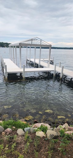 Narrow vertical view of a white boat slip canopy frame and pier extending into a Wisconsin lake