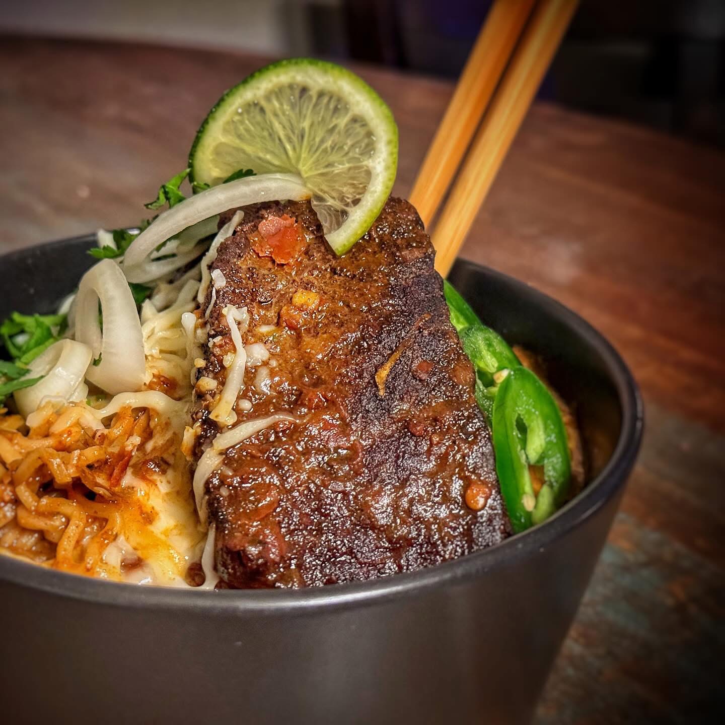 Short rib ramen bowl with lime, jalapeño, and chopsticks