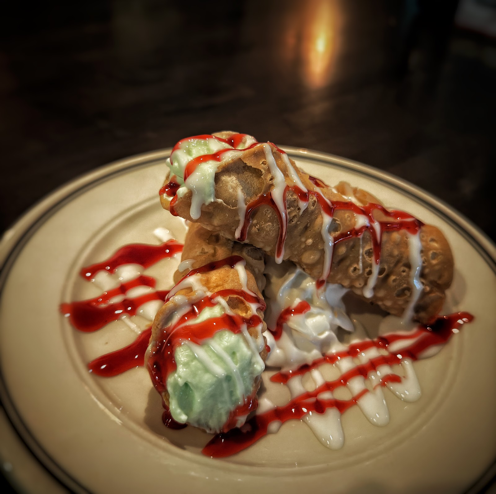 Filled cannoli drizzled with berry coulis and cream