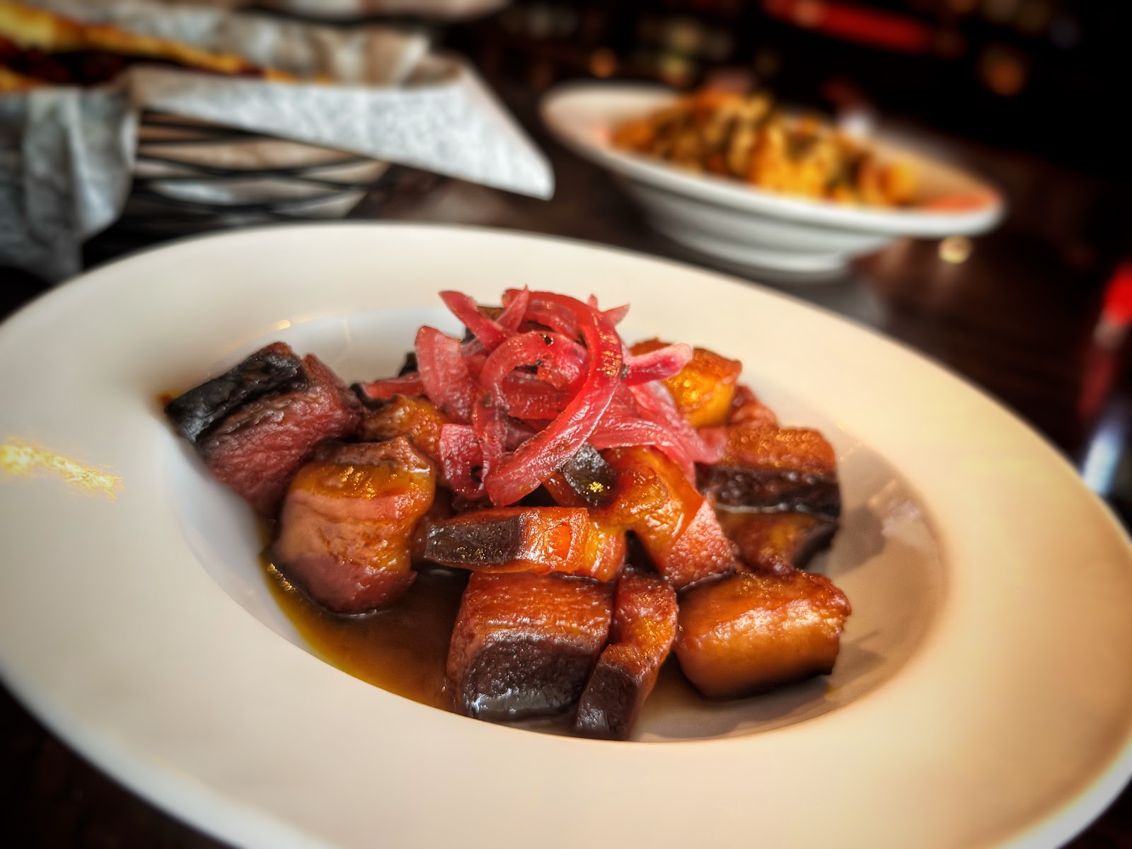 Glazed pork belly burnt ends topped with pickled red onions