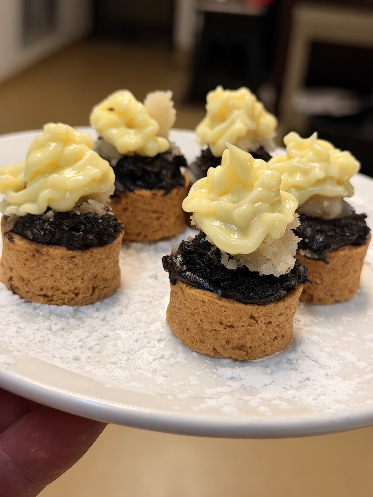 Individual dessert tartlets dusted with powdered sugar and piped cream