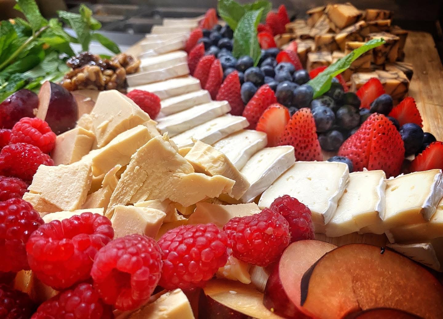 Plated artisan charcuterie board with fresh berries, plums, and cheeses