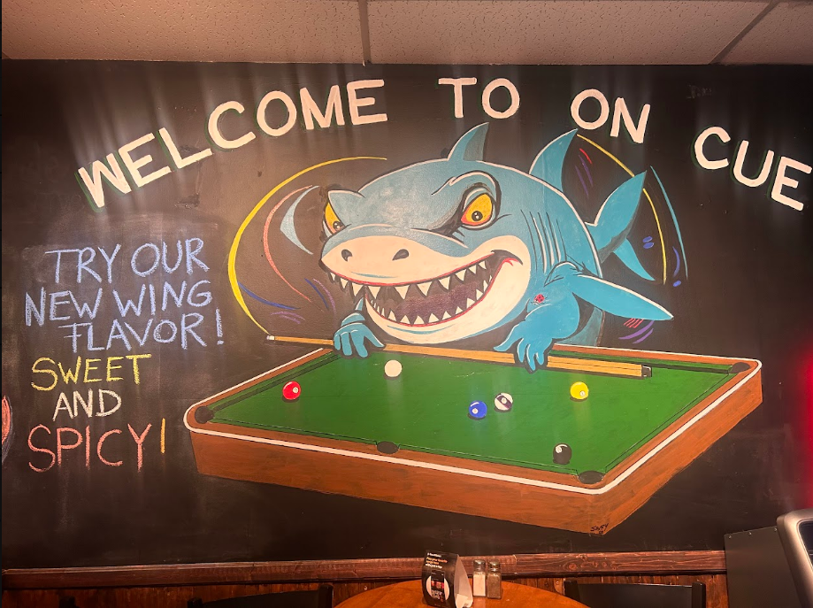 On Cue Billiards shark mural playing pool with chalkboard specials