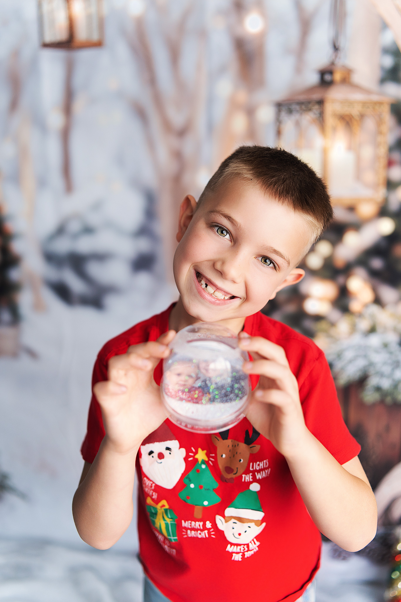 Boy holding up snow globe with warm Christmas lights