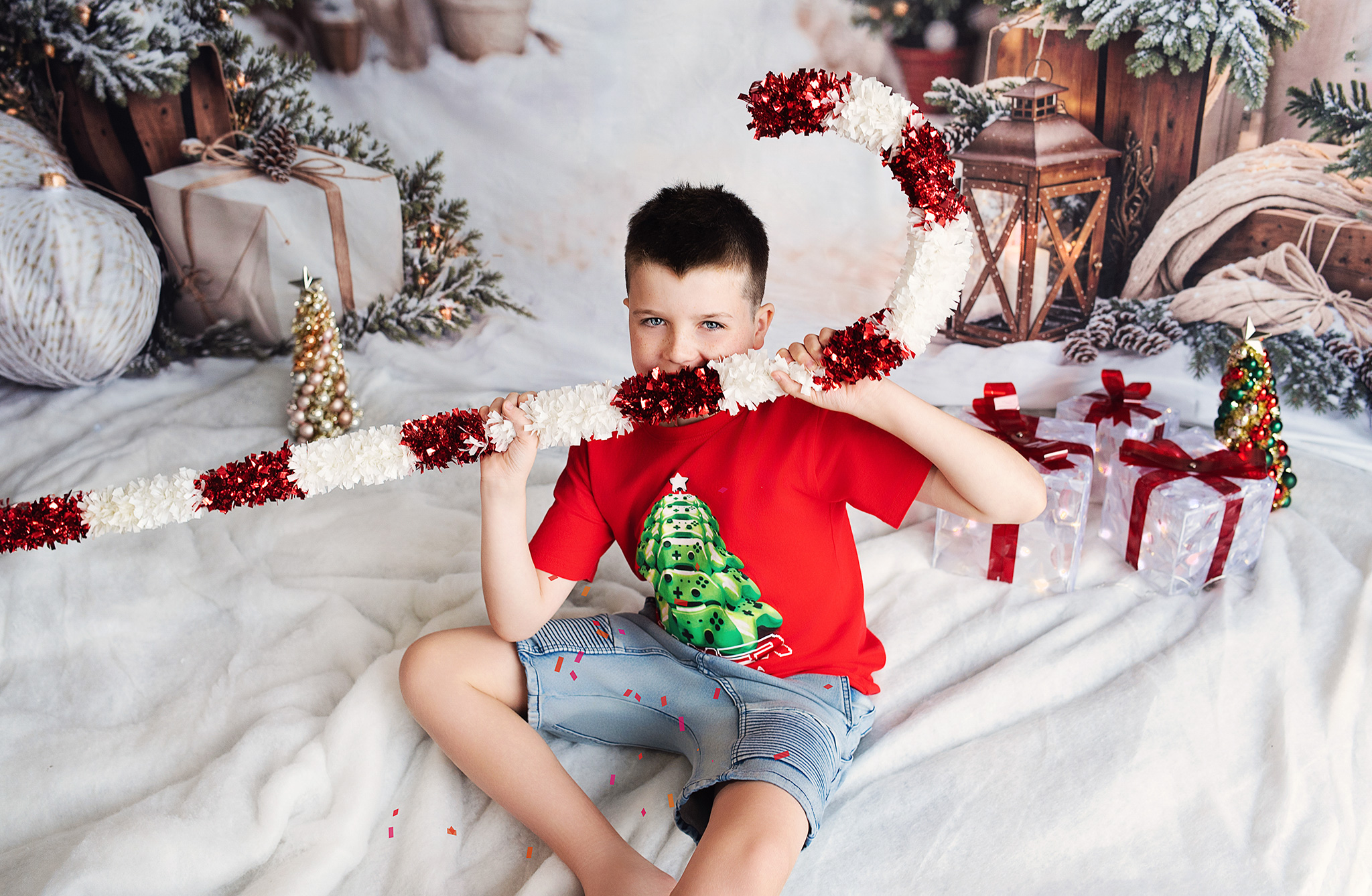 Boy holding sparkling giant candy cane in holiday setup