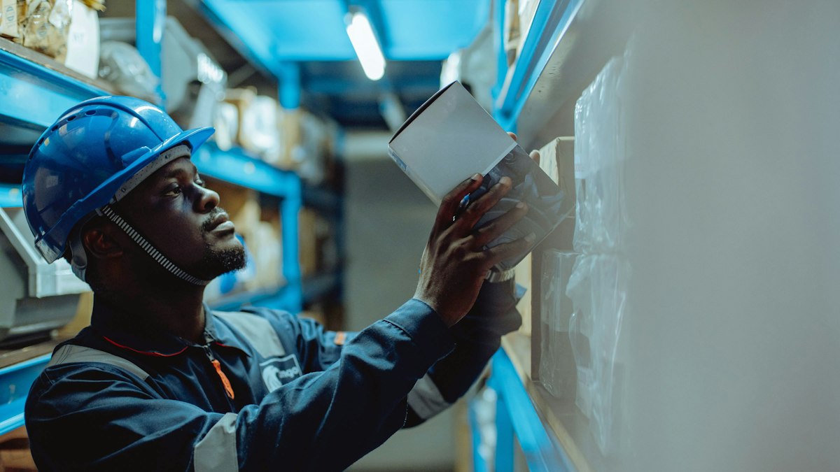 Warehouse worker in a hard hat checking a tablet