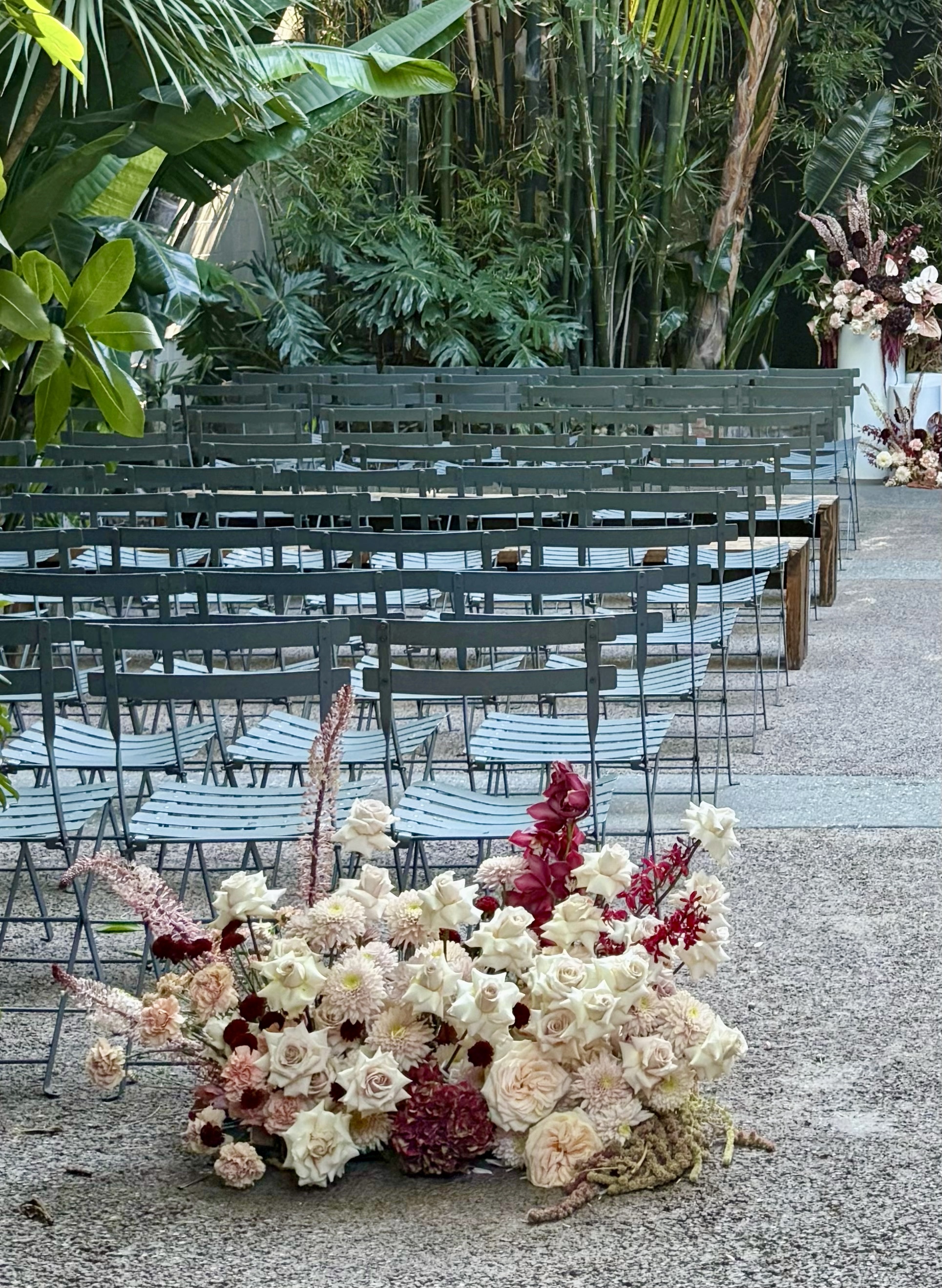 Ceremony aisle ground arrangement of white roses, blush dahlias and burgundy orchids by Soulform Florals, Los Angeles