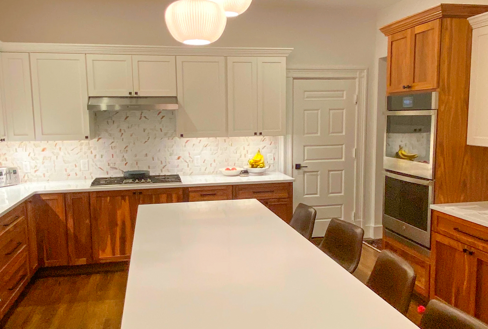 Custom two-tone kitchen with warm wood lower cabinets and white quartz island by KCC