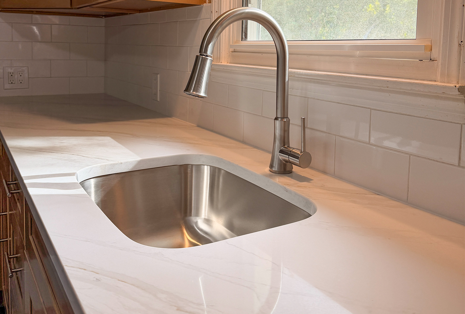 Marble-veined quartz countertop with undermount stainless steel sink and brushed faucet by KCC