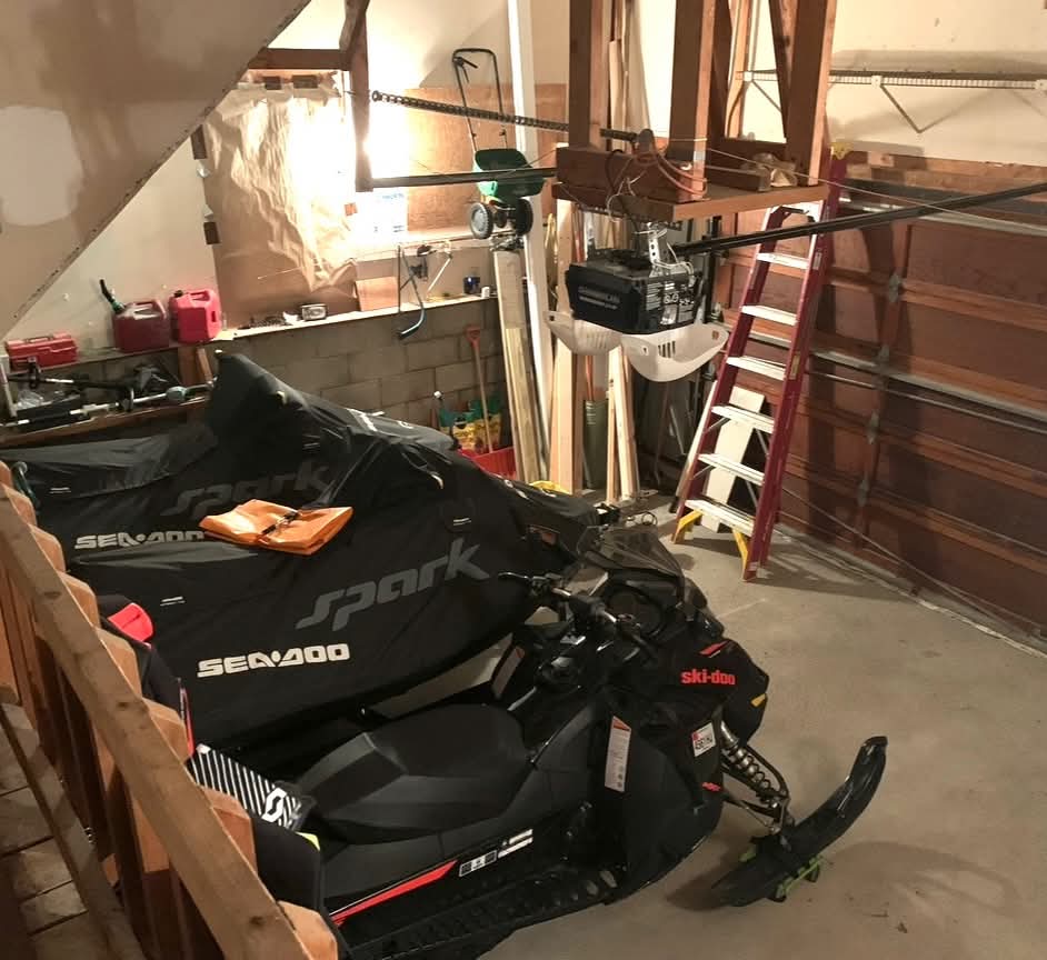 After: Cleared garage with clean floor and snowmobiles parked