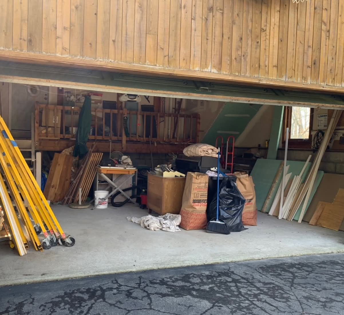 Before: Cluttered garage filled with wood, bags, and items