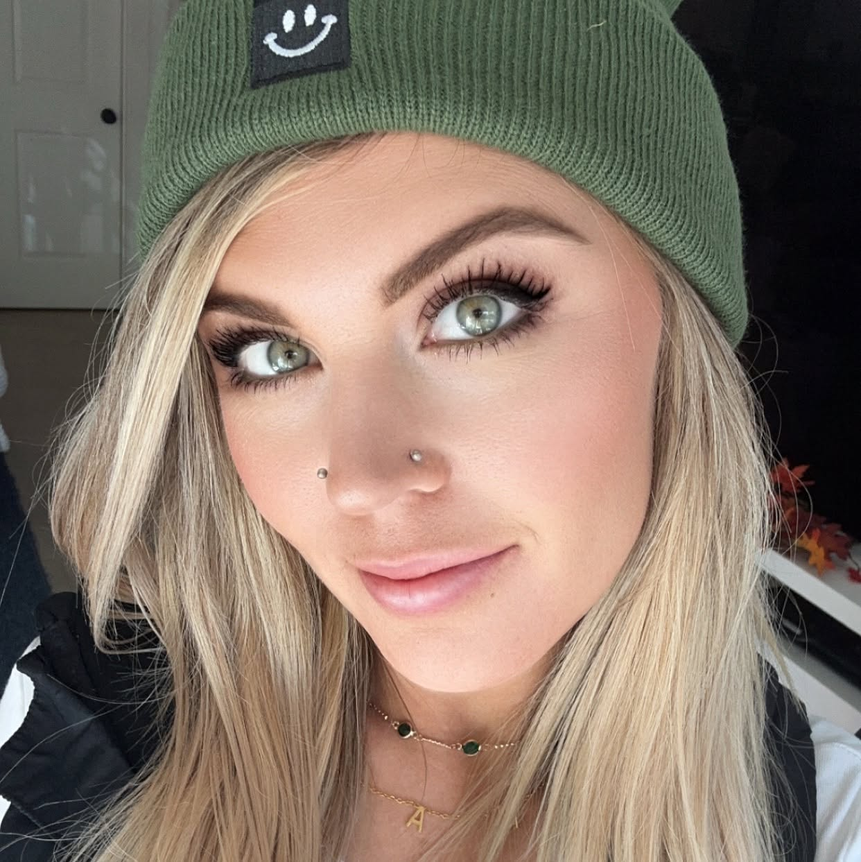 Tasha, licensed esthetician and founder of The Estie Bestie, wearing her green smiley beanie