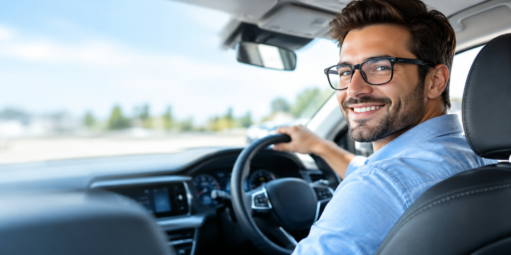 Smiling confident driver in glasses behind the steering wheel