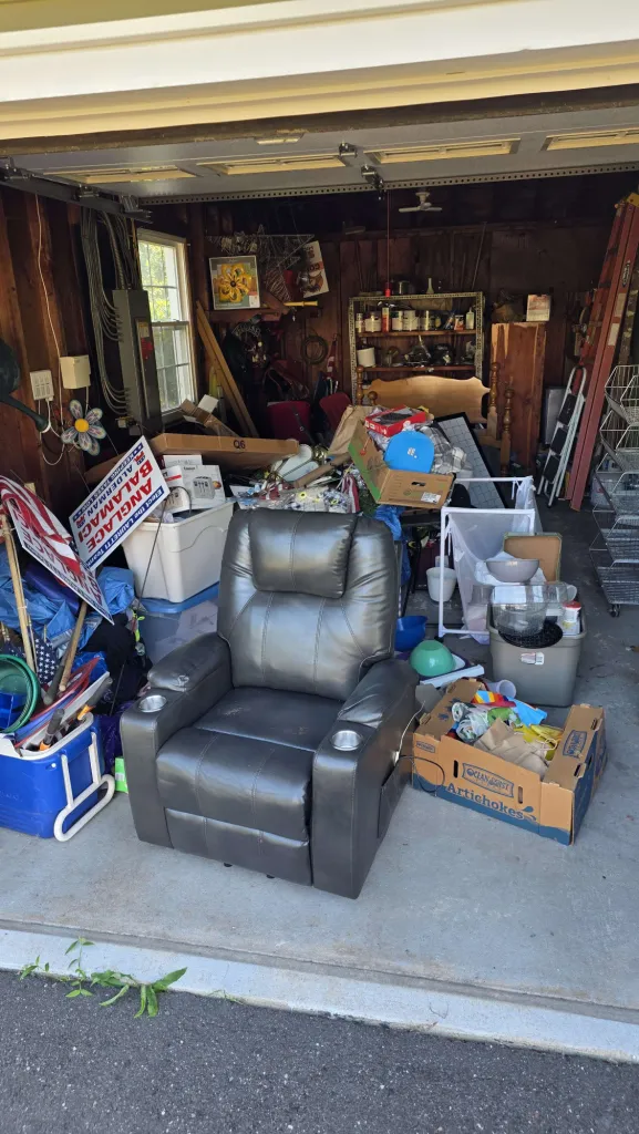 Packed garage filled with recliner, boxes, and accumulated clutter before Anchorline cleanout