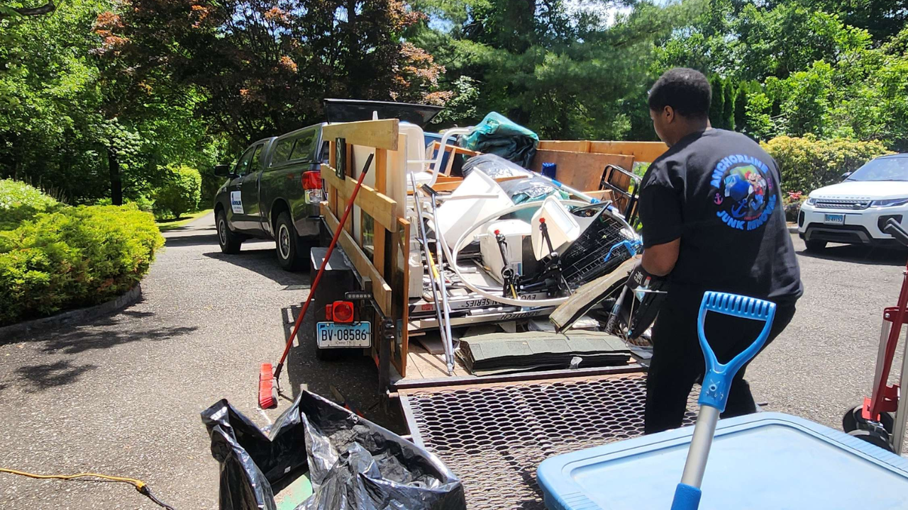 Anchorline crew member carefully handling items by the haul trailer during a residential cleanout in Fairfield County