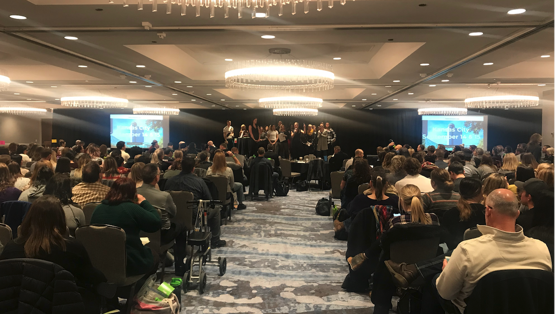 Karl and Brook leading a room full of team members at a regional training center.