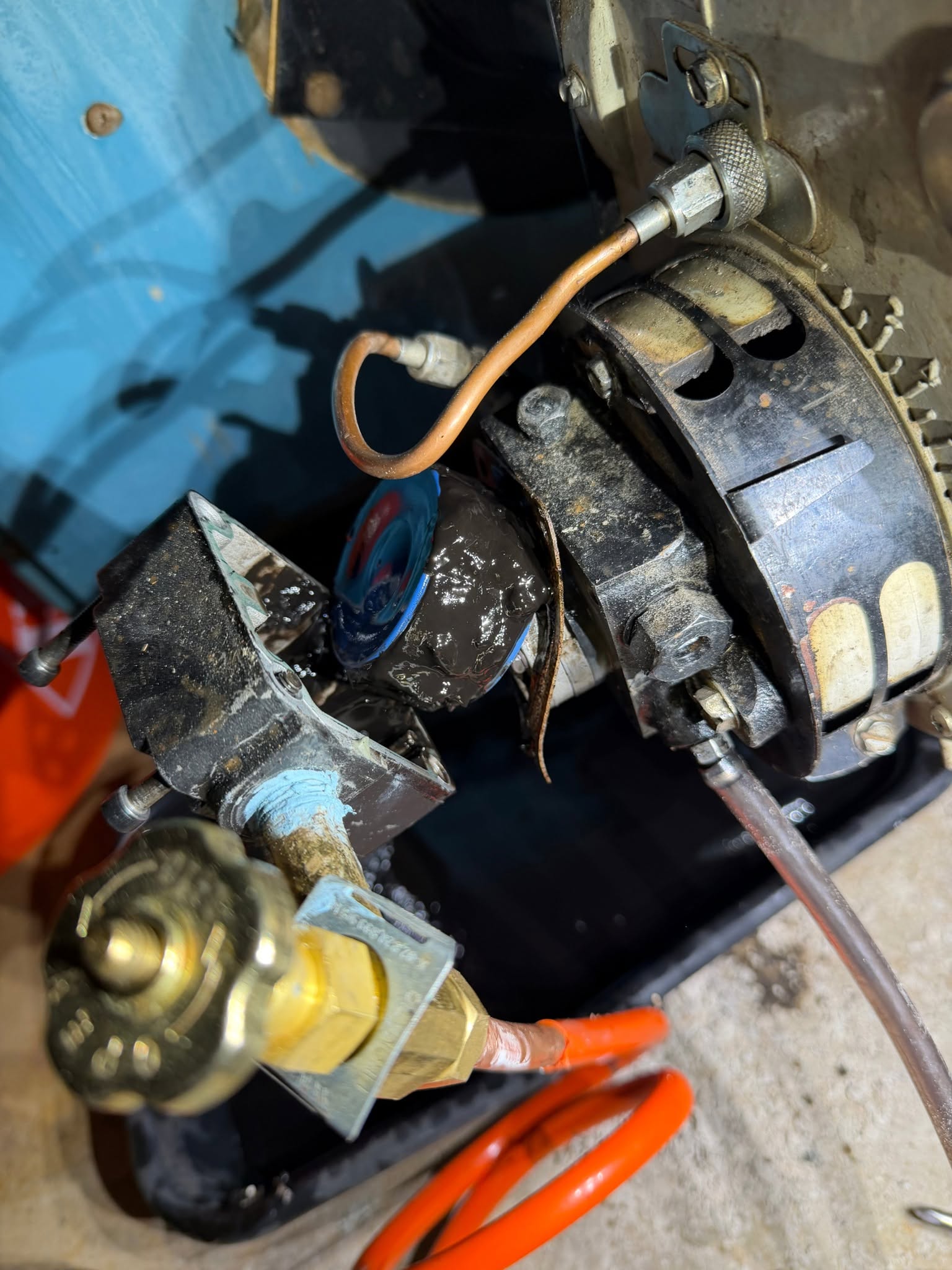 Disassembled oil burner fuel pump internal strainer basket coated in thick black petroleum sludge and sediment, demonstrating severe fuel line restriction before ultrasonic cleaning and nozzle replacement