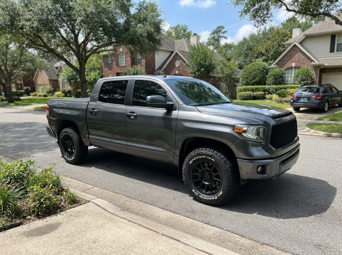 A pickup truck with custom powder-coated wheels parked on a suburban street on a sunny day